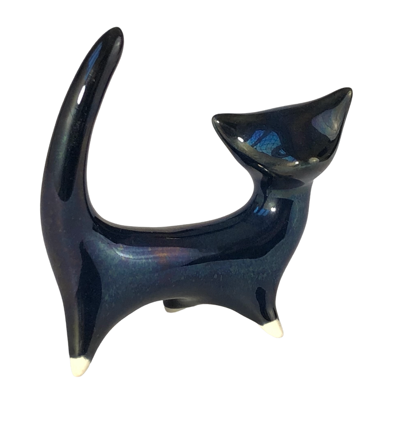 Photo 1, side view facing right: Mid-century ceramic cat with midnight-blue lustre glaze, a tall curved tail, pointed ears and cream-tipped feet.