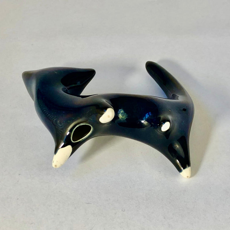 Underside of the ceramic cat showing its hollow opening, unglazed cream foot tips and unmarked base.