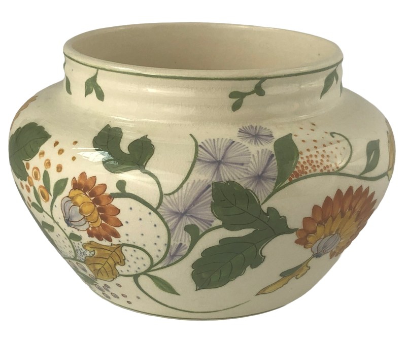 Rounded Gouda pottery cachepot with purple starburst flowers, ochre chrysanthemums and dark green leaves beneath a short flared rim.
