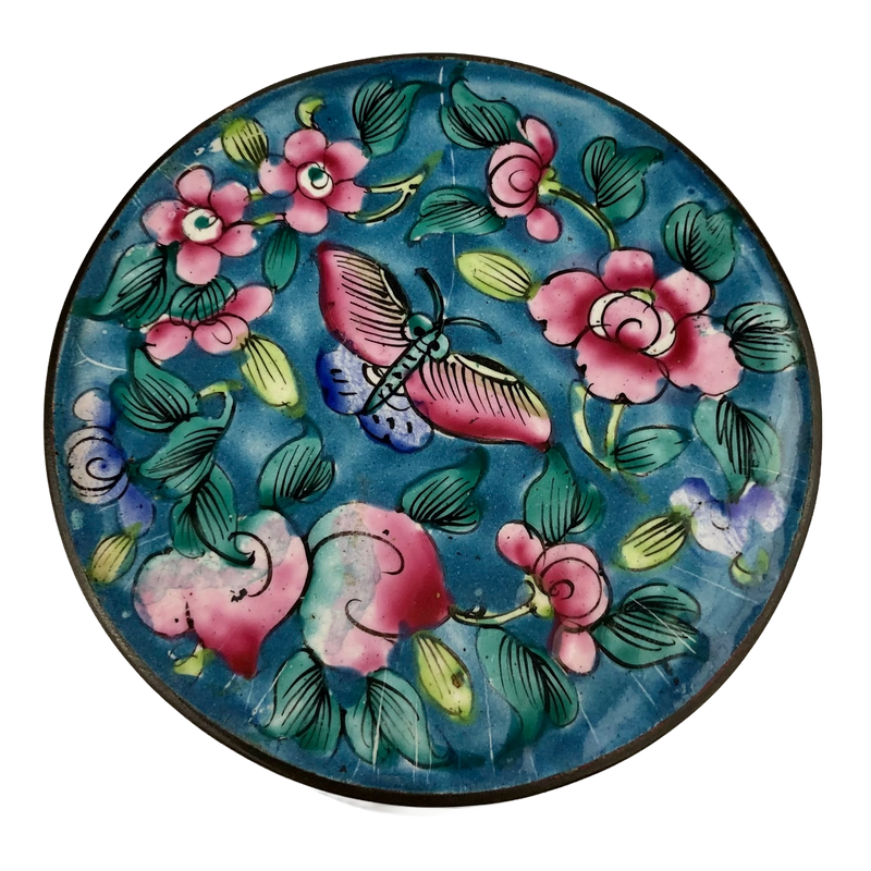 Top view of Canton enamel jar lid with a pink and blue butterfly surrounded by flowers and green foliage on turquoise.