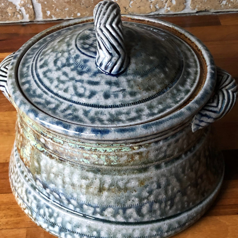 Angled view of Jane Hamlyn stoneware casserole showing the domed lid, patterned handle and textured salt glaze.