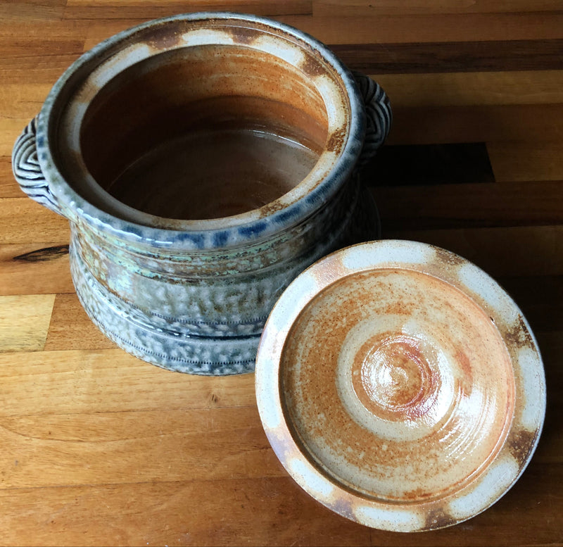 Open Jane Hamlyn casserole beside its upturned lid, showing the brown-glazed interior and cream and russet lid underside.