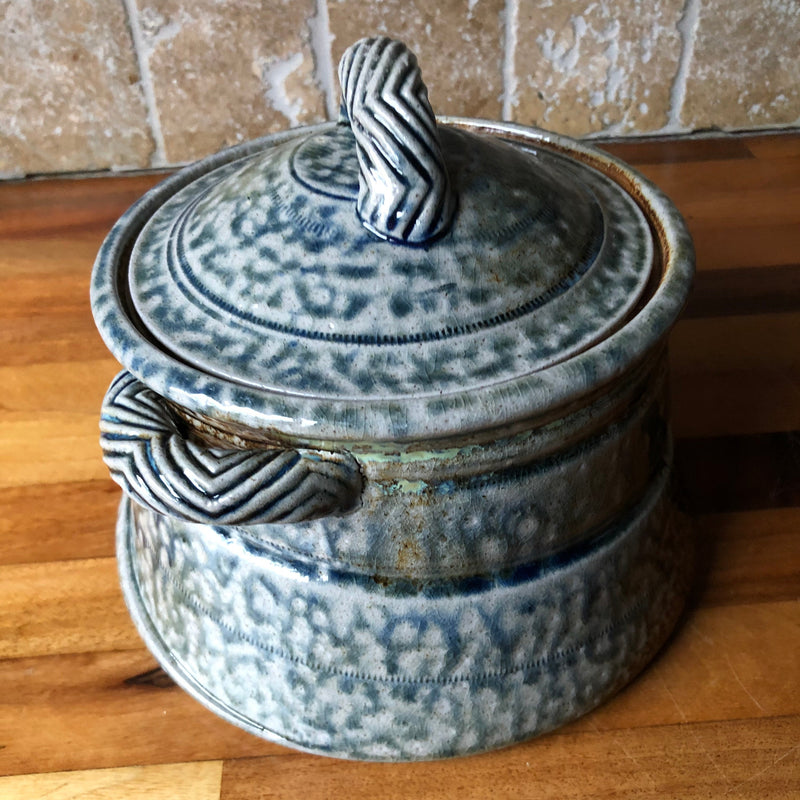 Side view of Jane Hamlyn salt-glazed casserole showing the chevron-patterned side handle and horizontal decorative bands.
