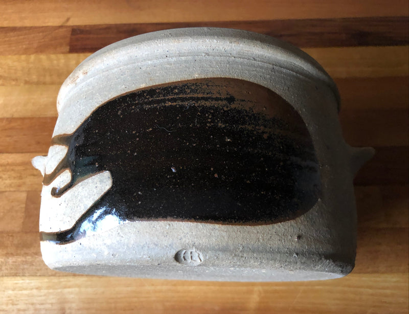 Photo 7, side and mark: Alan Brough casserole resting on its side, showing the broad dark brown brushstroke and impressed AB mark