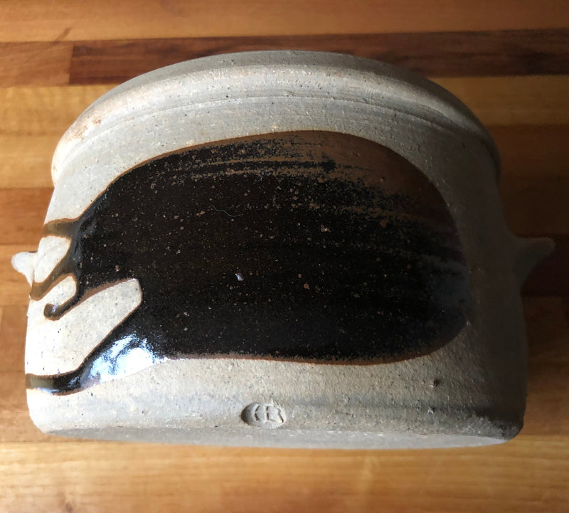 Side view of Alan Brough stoneware casserole showing glossy dark brown brushwork above the impressed AB maker’s mark.