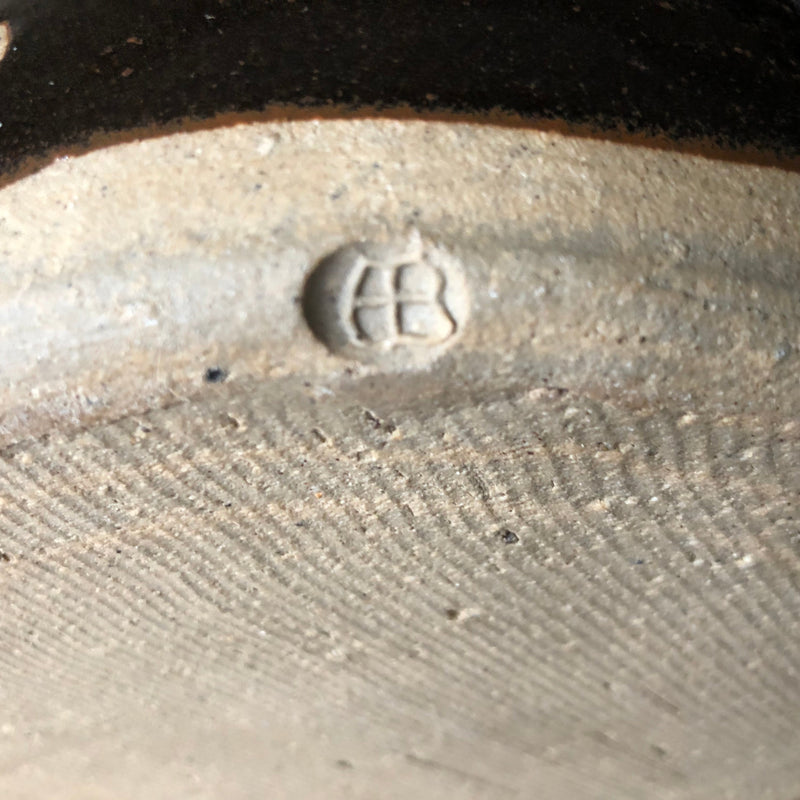 Detailed view of the impressed AB monogram on Alan Brough’s casserole, showing the surrounding textured stoneware.