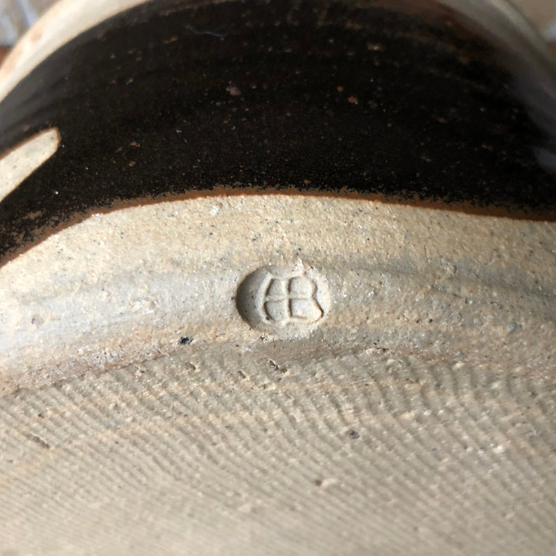 Alan Brough casserole resting on its side, showing the broad dark brown brushstroke and impressed AB mark near the base.