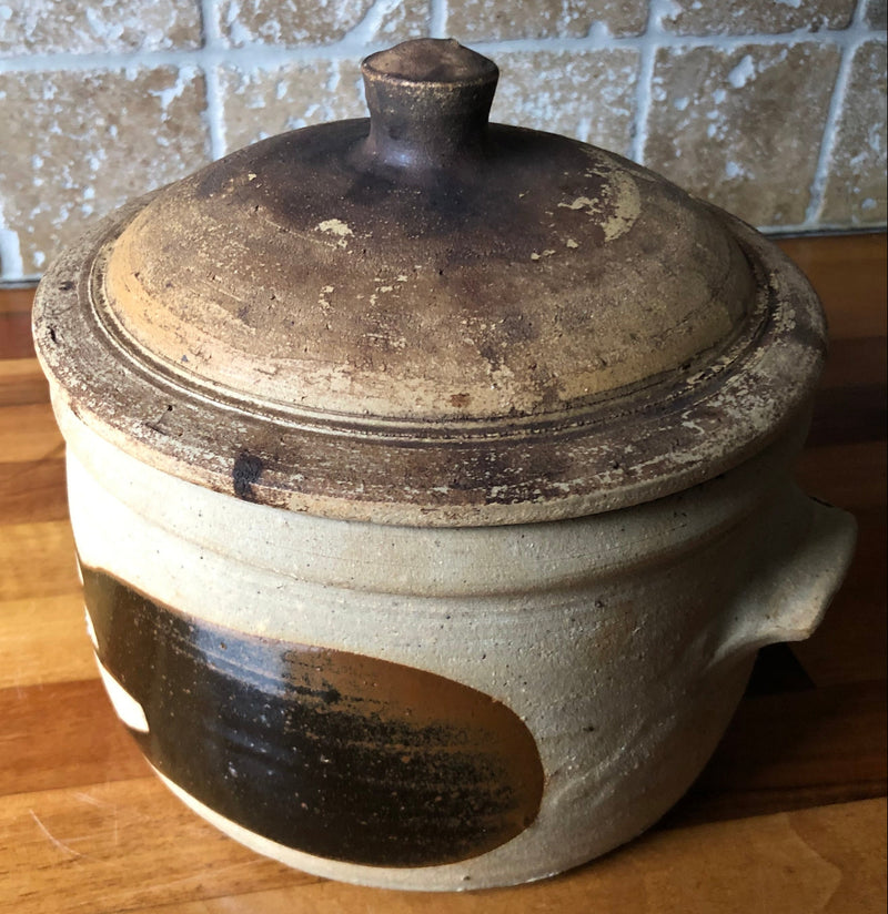 Angled view of Alan Brough casserole showing the mottled brown lid, raised knob and dark brushwork on the buff body.