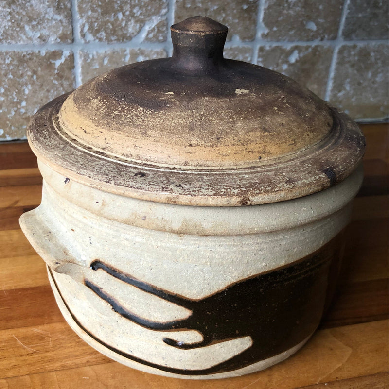 Alan Brough lidded stoneware casserole showing sweeping dark brown decoration and a small side handle.