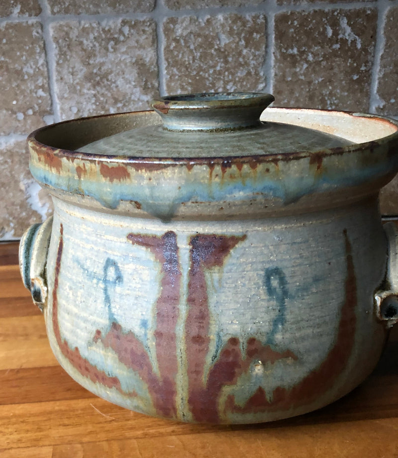 Front detail of Vera Tollow lidded stoneware casserole showing rust-red brushwork against a pale blue-grey glaze.