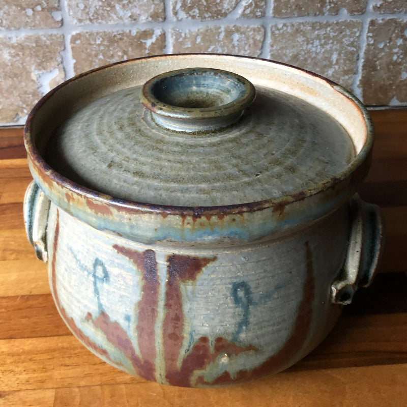 Vera Tollow stoneware casserole viewed from above at an angle, showing the recessed lid and rust-red painted decoration.