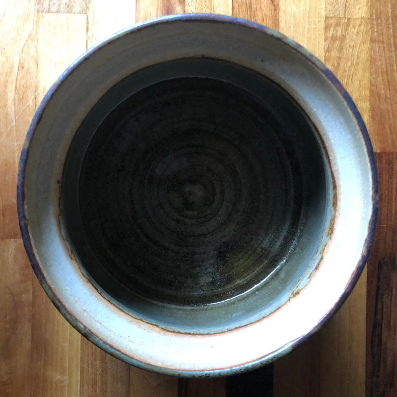 Overhead view inside Vera Tollow stoneware casserole showing the dark glazed interior, throwing rings and broad pale rim.