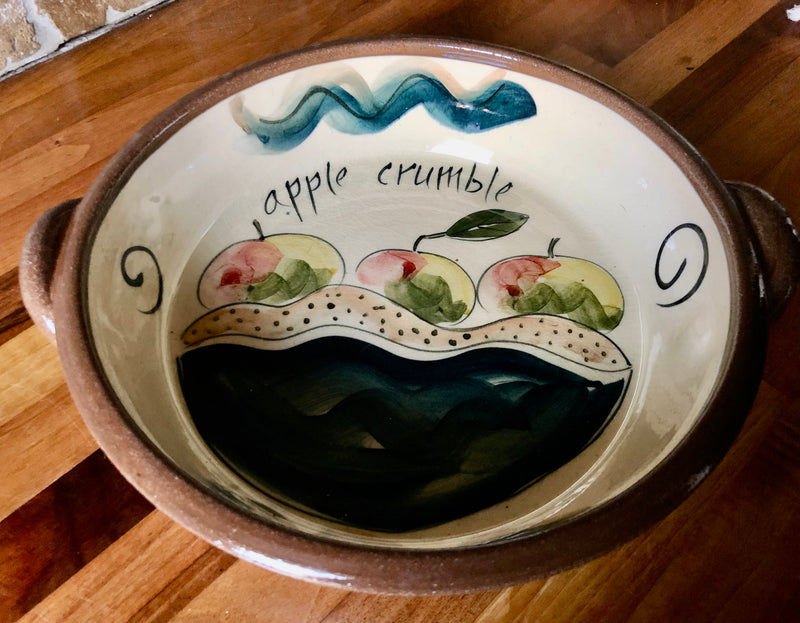 Hand-painted apple crumble dish attributed to Philippa Lee, with apple decoration, cream glaze and two side handles.
