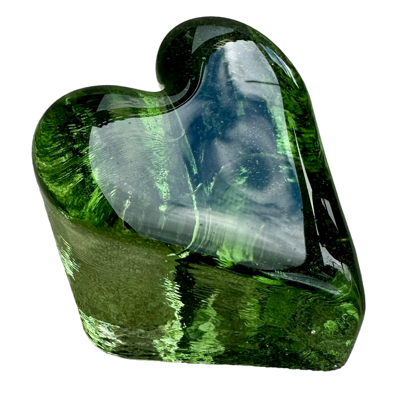 Fire & Light green glass heart paperweight viewed from above at an angle, showing its smooth face and thick sides.
