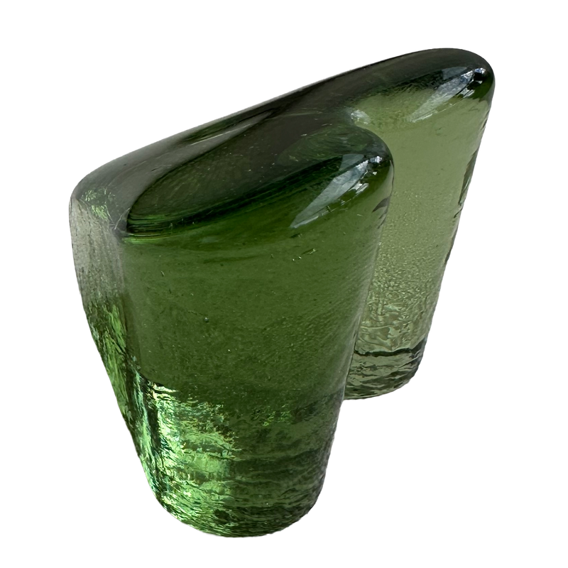 Side view of the Fire & Light green glass heart paperweight showing its depth and rounded lobes.