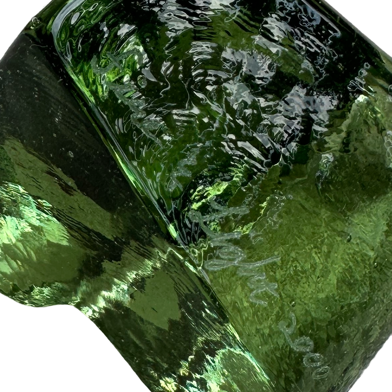 Close-up of  signature and the rippled surface and tiny bubbles in the Fire & Light green glass heart paperweight.
