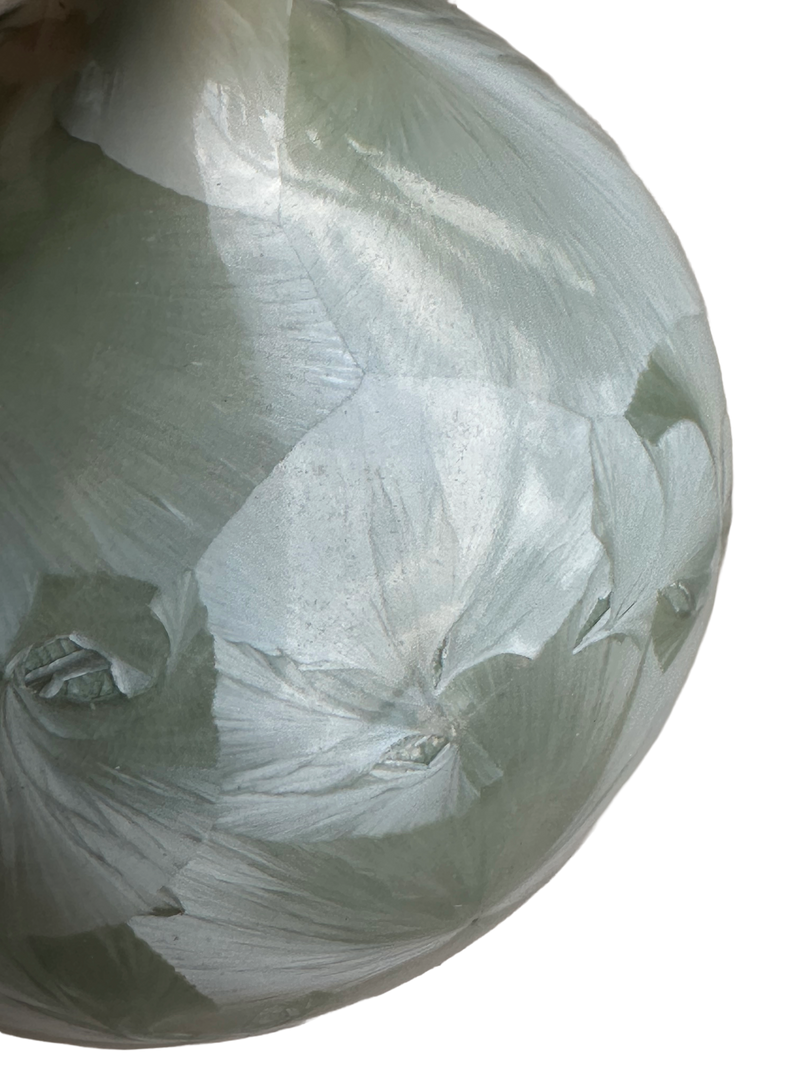 Close-up of overlapping, feather-like crystal formations in the sage-green glaze of the Louise Reding porcelain vase