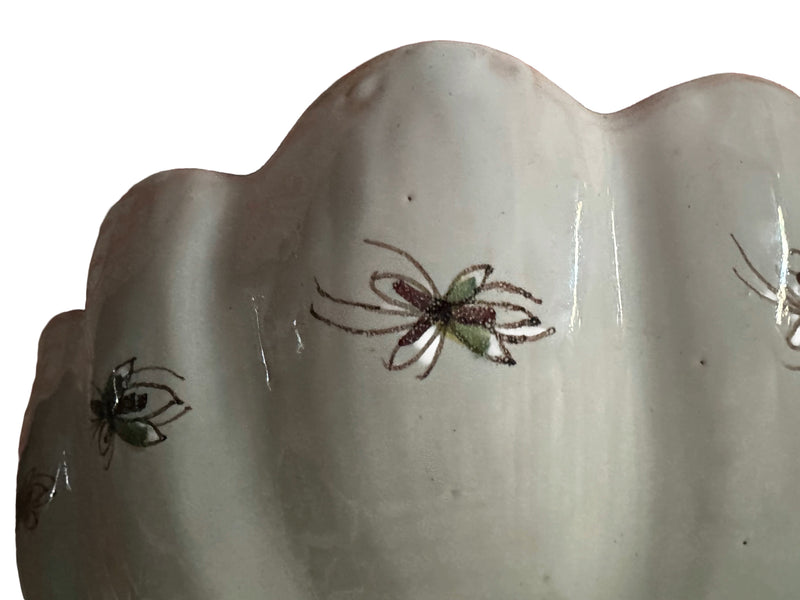  Close-up of exterior rim, underside Exterior underside of Portuguese Coimbra faience centrepiece bowl showing cream glaze with delicate hand-painted insect and floral motifs in green and manganese
